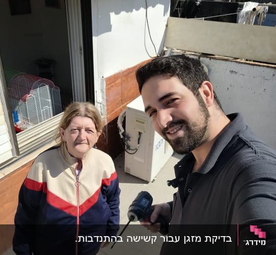 טכנאי עם מקדחה ליד מזגן חיצוני על קיר
